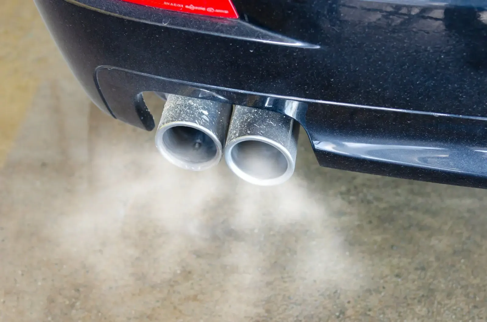 Car exhaust tailpipes releasing white exhaust smoke. Southwest Muffler & Brake, Stafford and Houston.