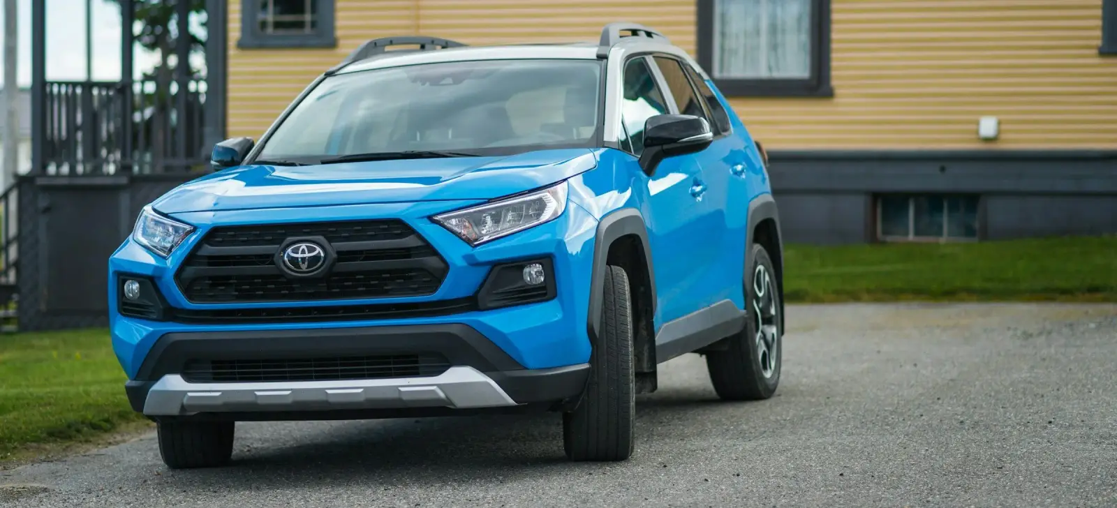 Blue Toyota RAV4 parked in front of a yellow house. Southwest Muffler & Brake, Stafford and Houston.