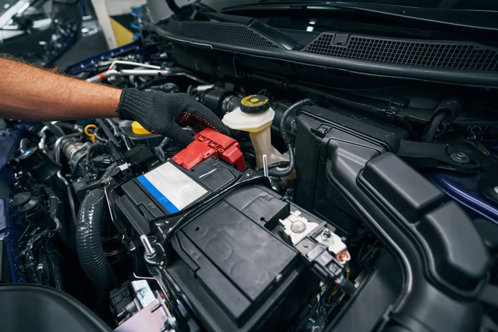 Mechanic installing car battery in engine bay. Southwest Muffler & Brake, Stafford and Houston.