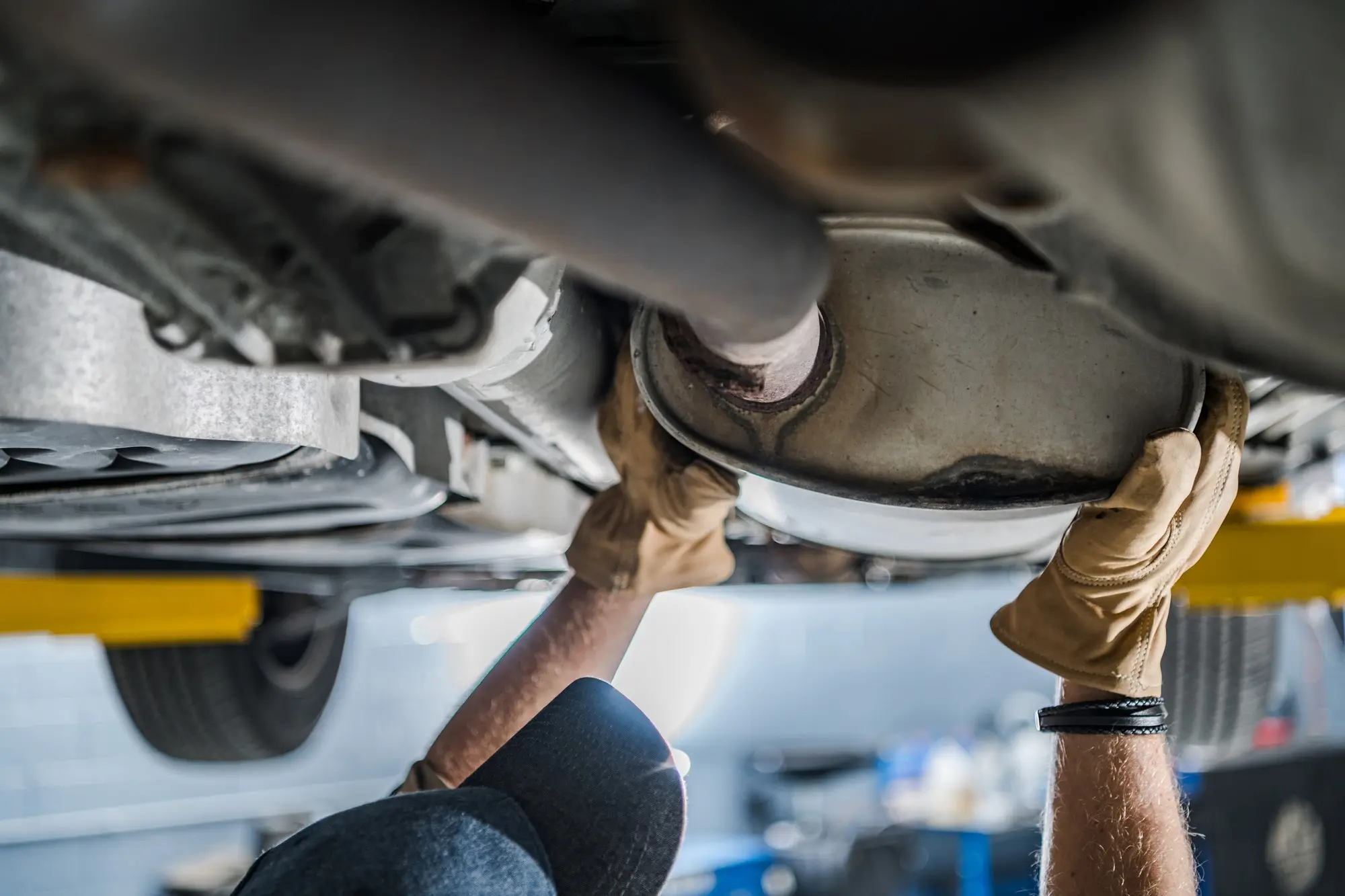 Mechanic inspecting exhaust system underneath vehicle. Southwest Muffler & Brake, Stafford and Houston.