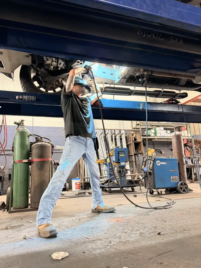 Technician using a hand tool beneath a raised vehicle at Southwest Muffler & Brake in Houston.