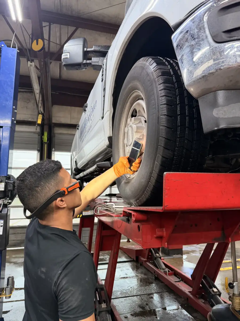 Technician in safety glasses and orange gloves working at a truck wheel at Southwest Muffler & Brake in Stafford.